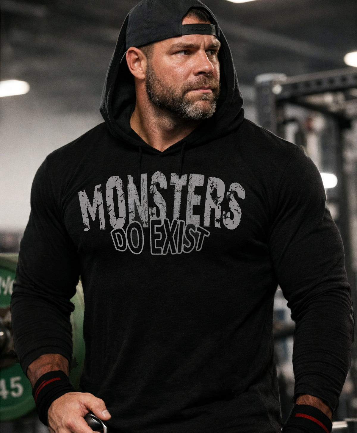 Man wearing a black hoodie with 'MONSTERS DO EXIST' text in a gym setting, Black pump cover, black hodie, gym hoodie
